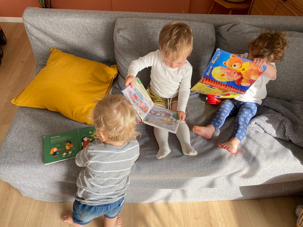 Drei Kinder schauen Bücher auf dem Sofa
