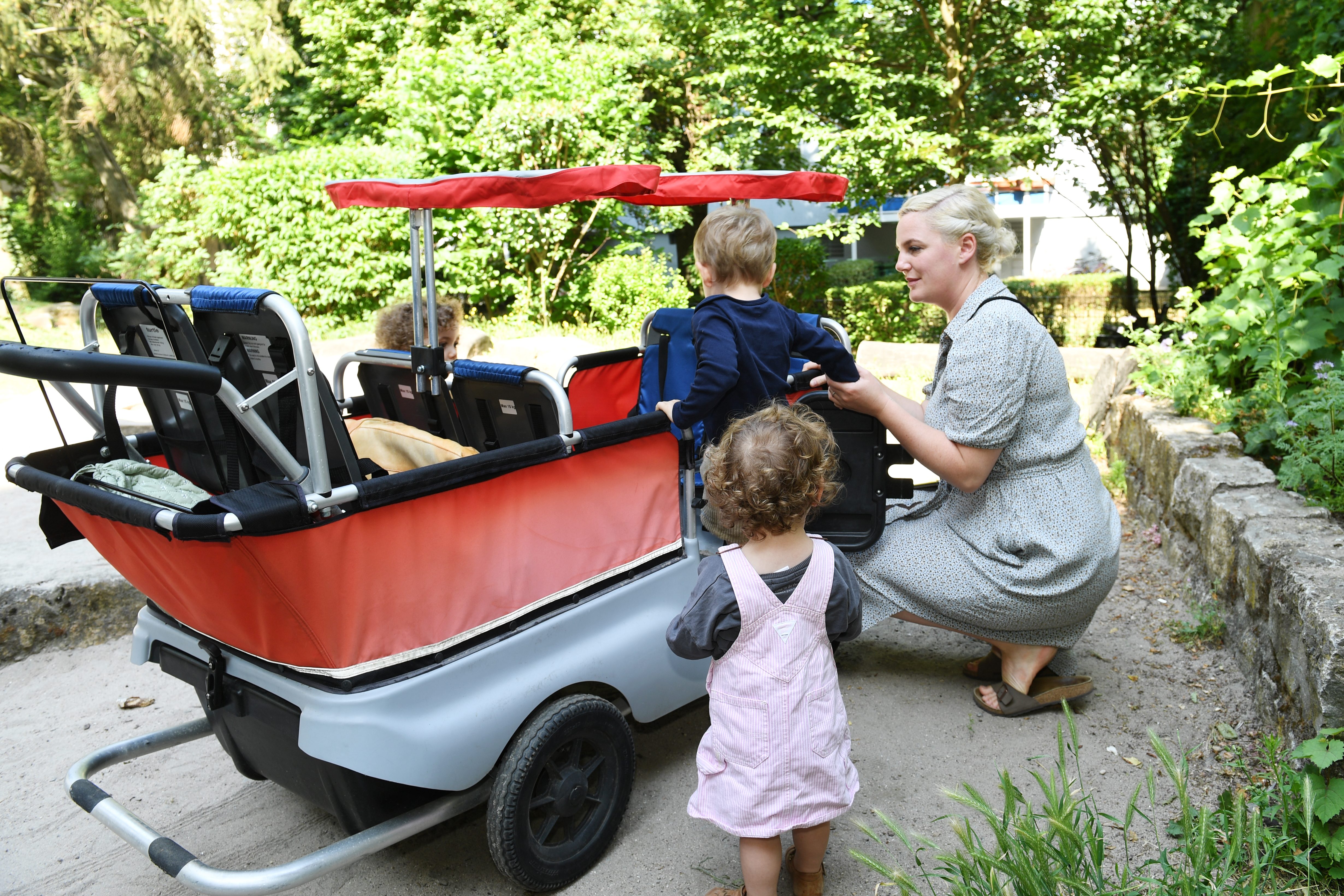 Tita hilft einem Kind beim Einsteigen in den Turtlebus