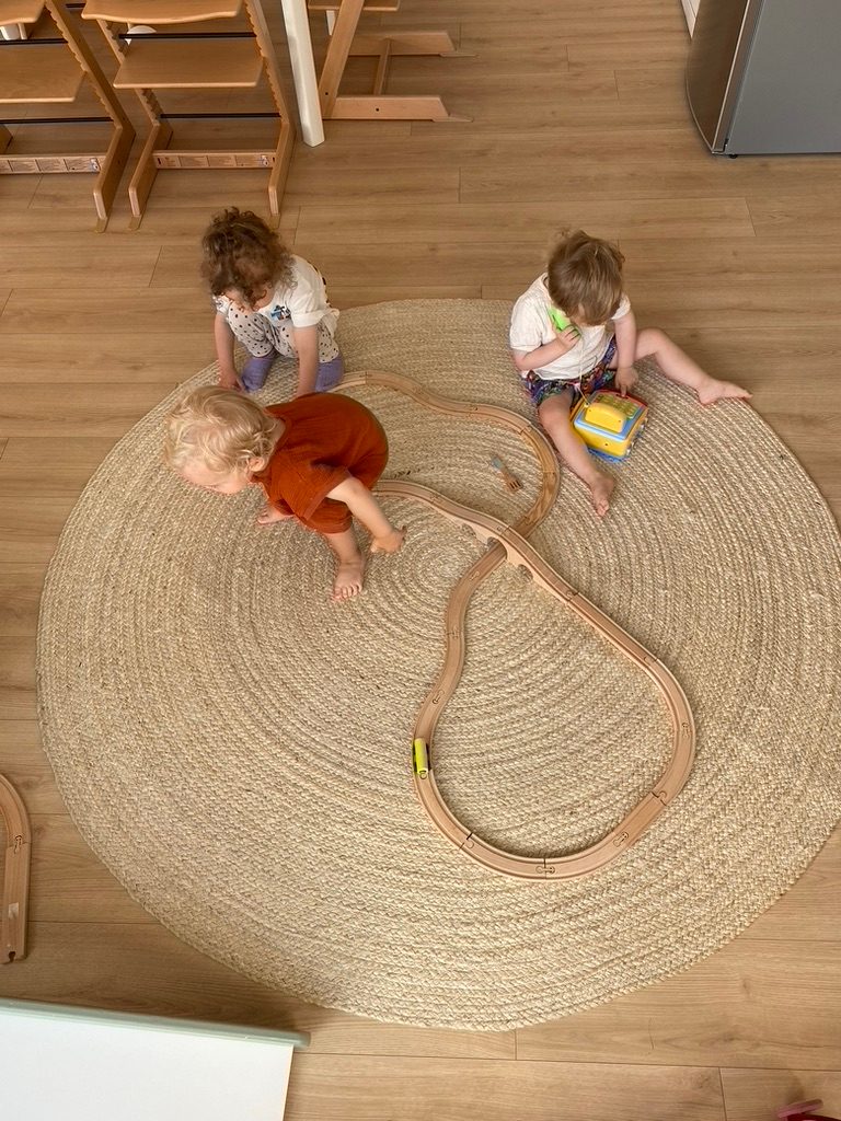Drei Kinder spielen gemeinsam mit der Holzeisenbahn