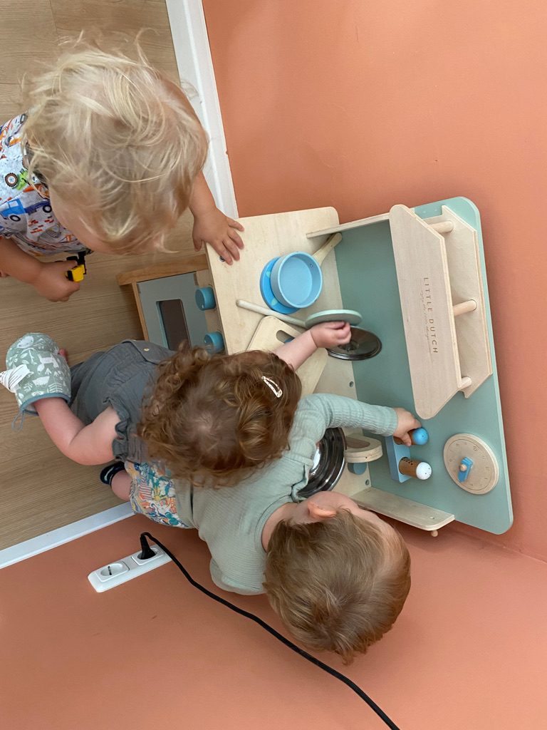 Drei Kinder spielen an der Kinderküche