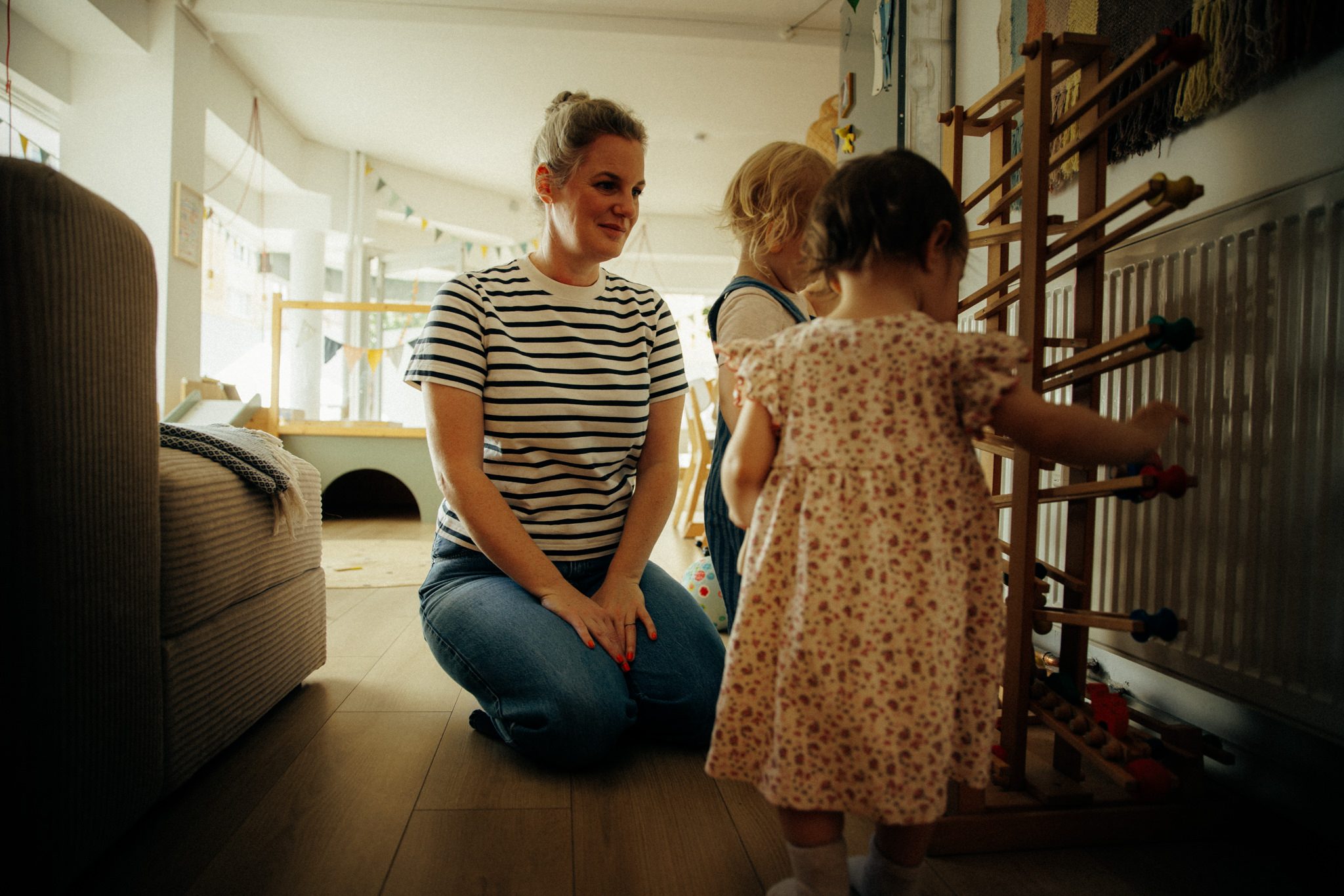 Tita spielt mit zwei Kindern am Regal im Flur